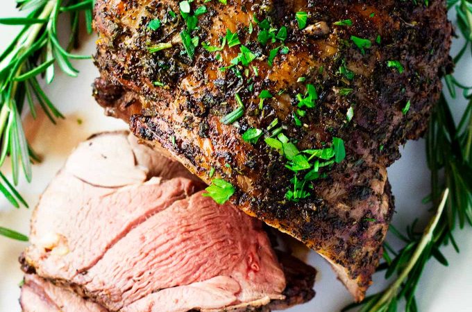 This perfect roasted boneless leg of lamb will make your mouth water. It's rubbed with a paste of olive oil and herbs and stuffed with garlic slivers. It's sure to be a hit on any holiday or in any dinner setting!